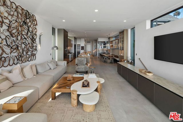 a living room with stainless steel appliances furniture a rug and a kitchen view