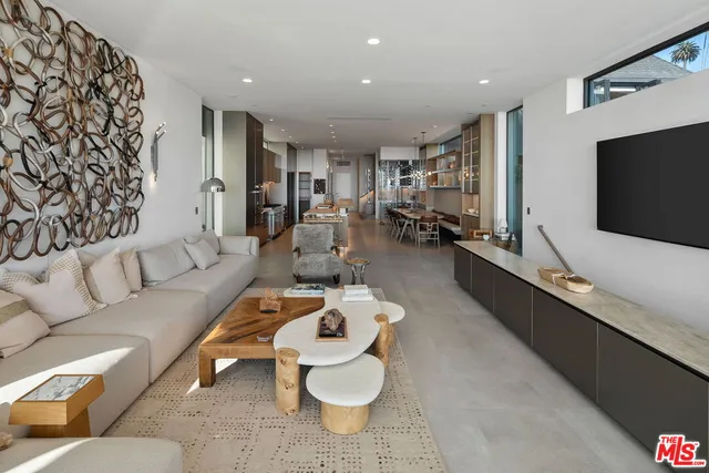 a living room with stainless steel appliances furniture a rug and a kitchen view