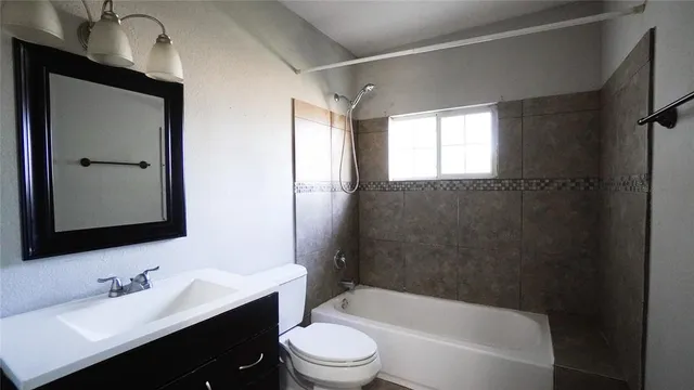 a bathroom with a bathtub shower sink vanity mirror and toilet