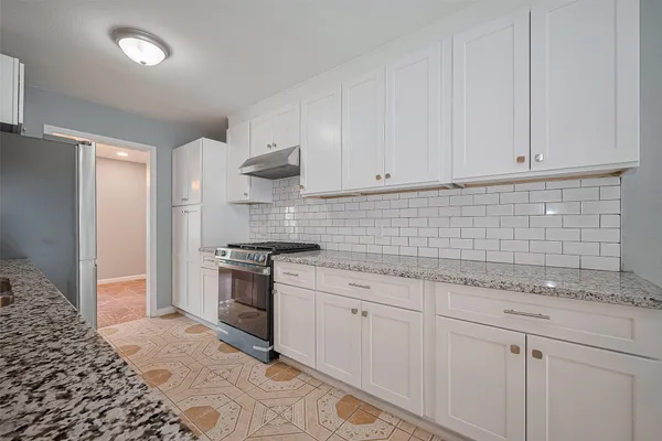 a kitchen with granite countertop white cabinets and stainless steel appliances