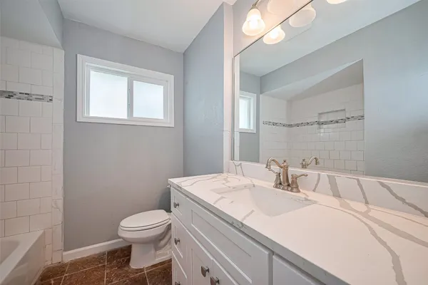 a bathroom with a sink toilet vanity and window