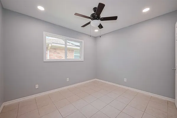an empty room with a ceiling fan and window