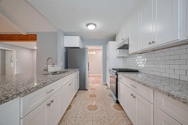 a large kitchen with granite countertop white cabinets and a stainless steel appliances
