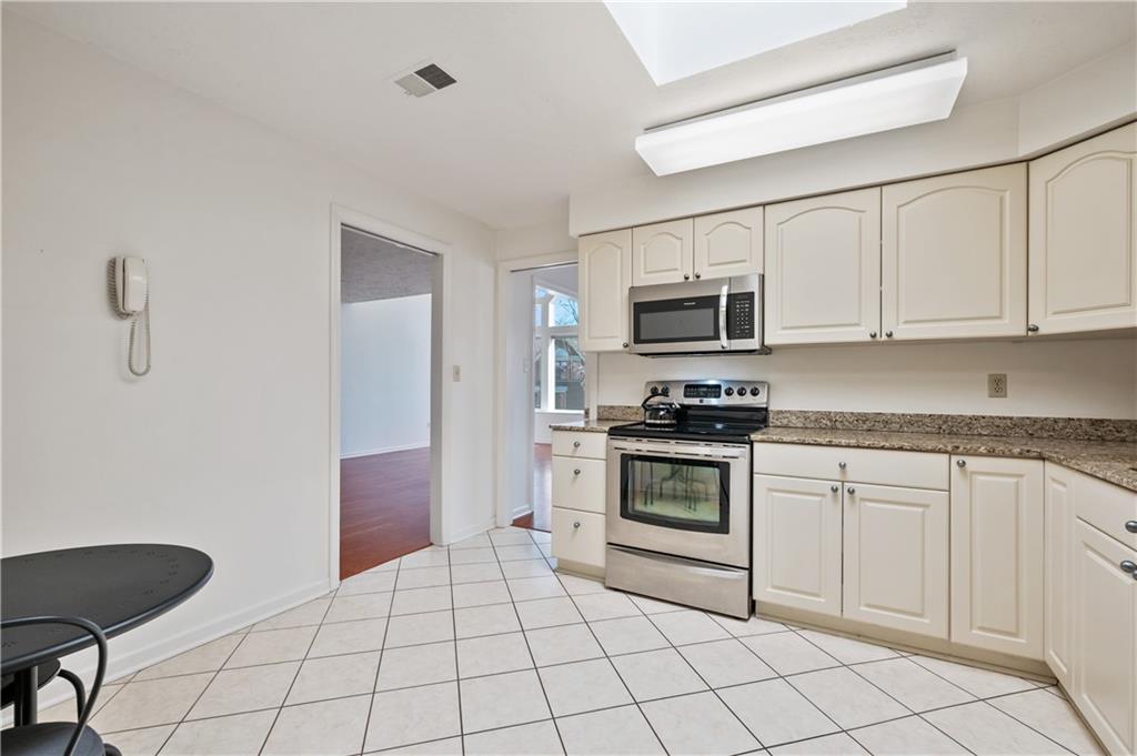 100 Denniston Street, Unit 304 Pittsburgh, PA 15206 - Photo 12 of 27 a kitchen with granite countertop a stove top oven microwave and cabinets