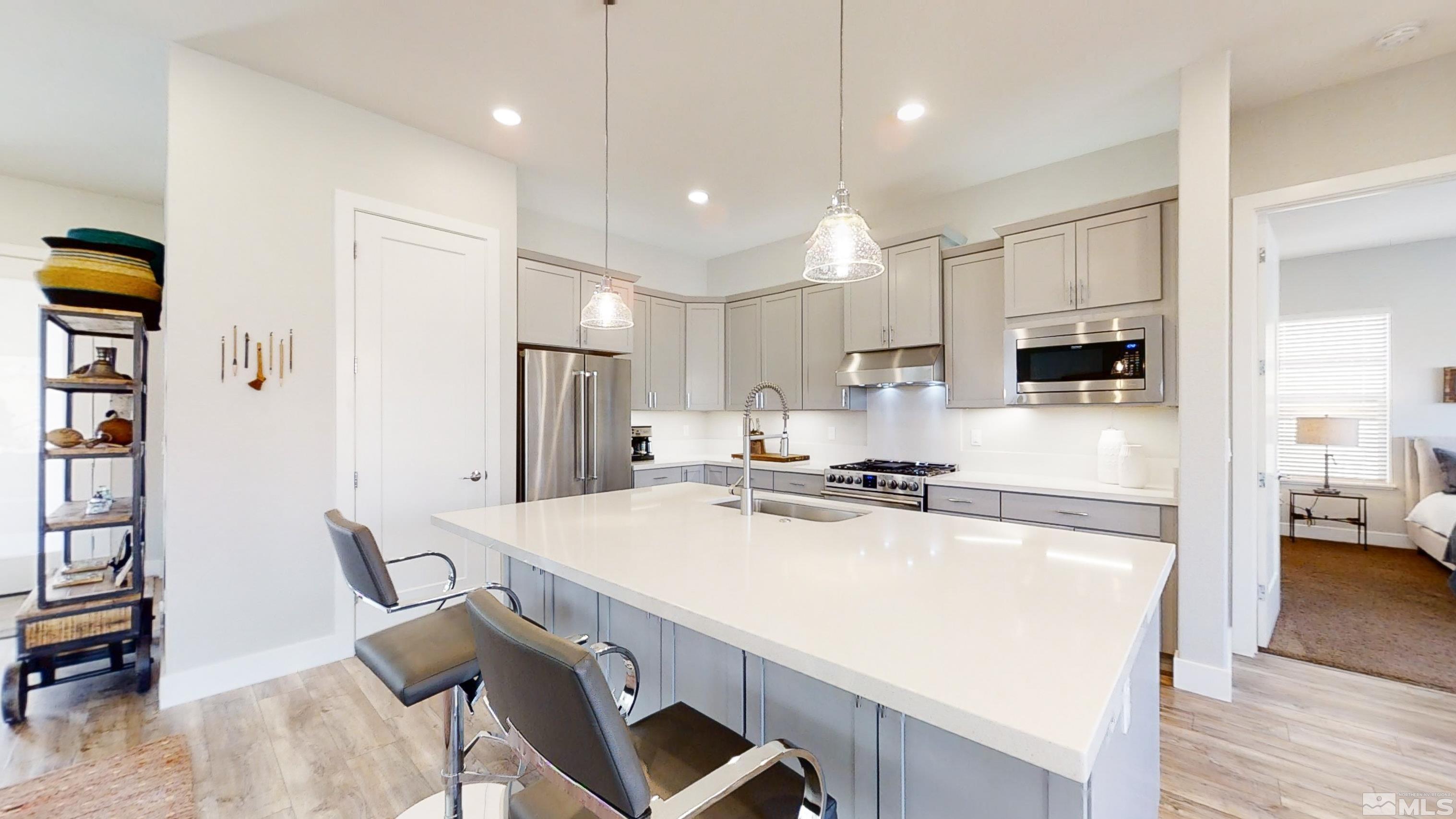 8779 Larkhaven Trail Reno, NV 89523 - Photo 10 of 32 a kitchen with stainless steel appliances a stove a sink a refrigerator white cabinets and chairs