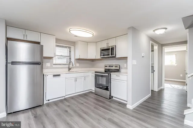 a kitchen with white cabinets stainless steel appliances and a refrigerator