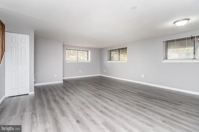 an empty room with wooden floor and windows