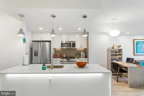 a kitchen with stainless steel appliances kitchen island granite countertop a refrigerator a stove a sink and a dining table with wooden floor