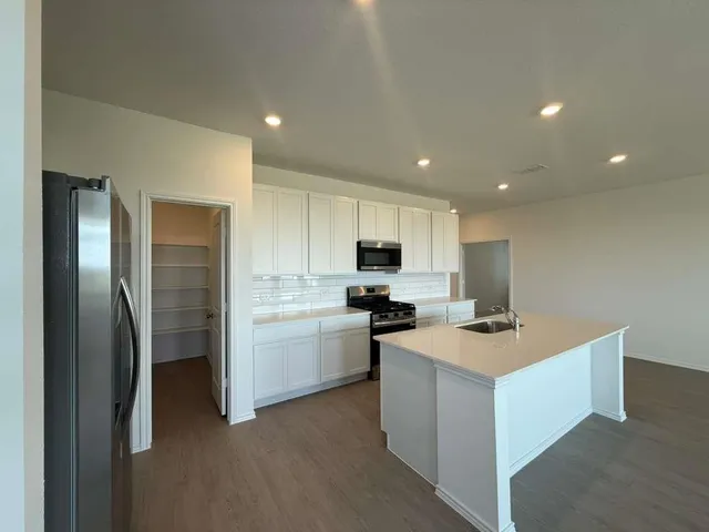 a kitchen with stainless steel appliances kitchen island sink refrigerator and cabinets