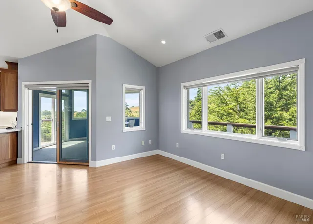 a view of an empty room with window and wooden floor