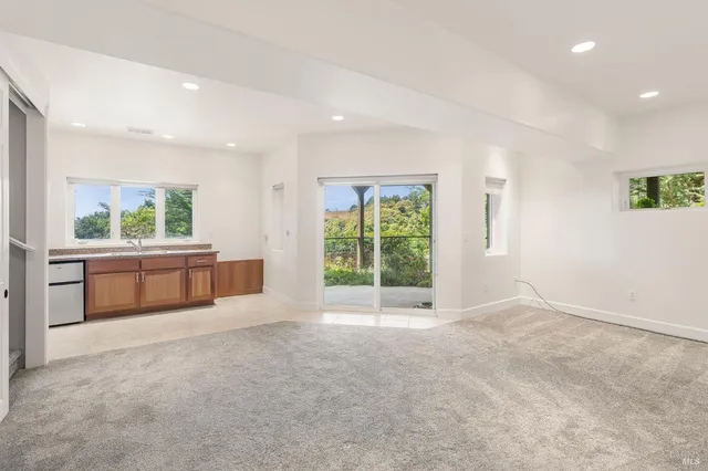 a view of an empty room with a window and a kitchen