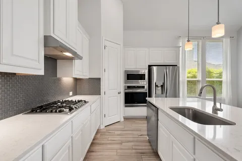 a kitchen with granite countertop a sink stainless steel appliances and cabinets