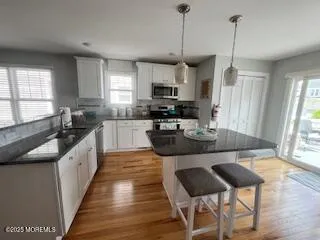 a kitchen with stainless steel appliances granite countertop a sink a stove top oven a counter space and wooden floor