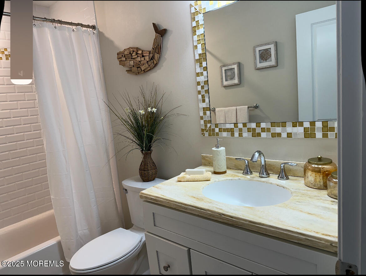 2105 Grand Central Avenue, Unit 1 Lavallette, NJ 08735 - Photo 22 of 33 a bathroom with a granite countertop sink a toilet a mirror and shower curtain