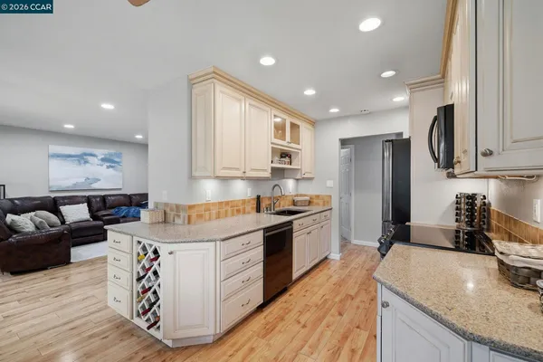 a kitchen with granite countertop white cabinets and stainless steel appliances