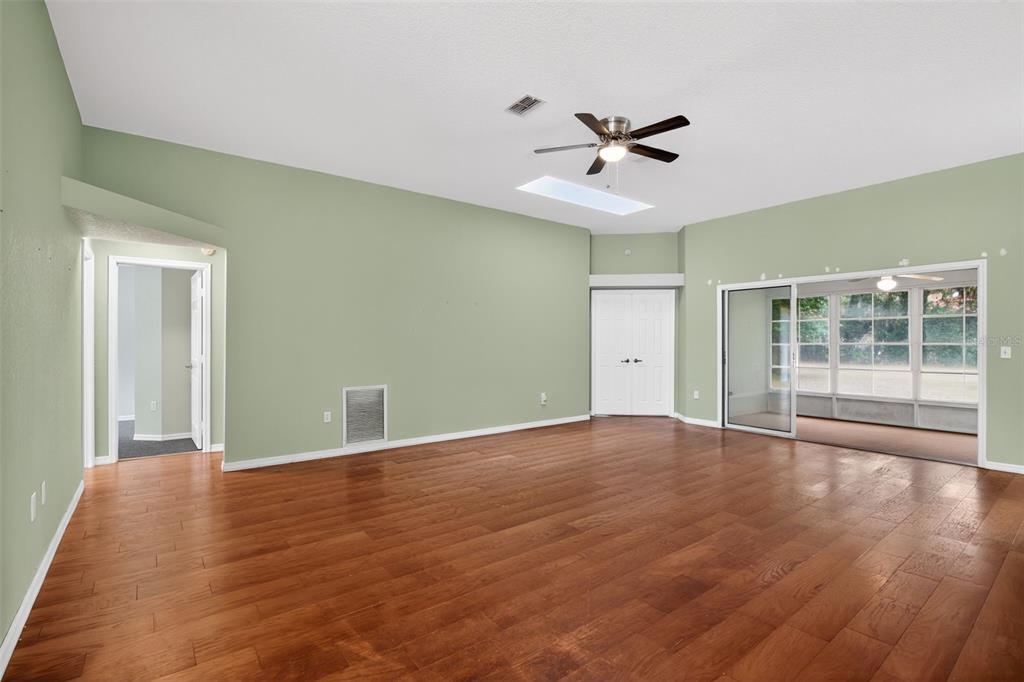 11443 Southwest 78th Circle Ocala, FL 34476 - Photo 2 of 33 a view of an empty room with wooden floor and a ceiling fan