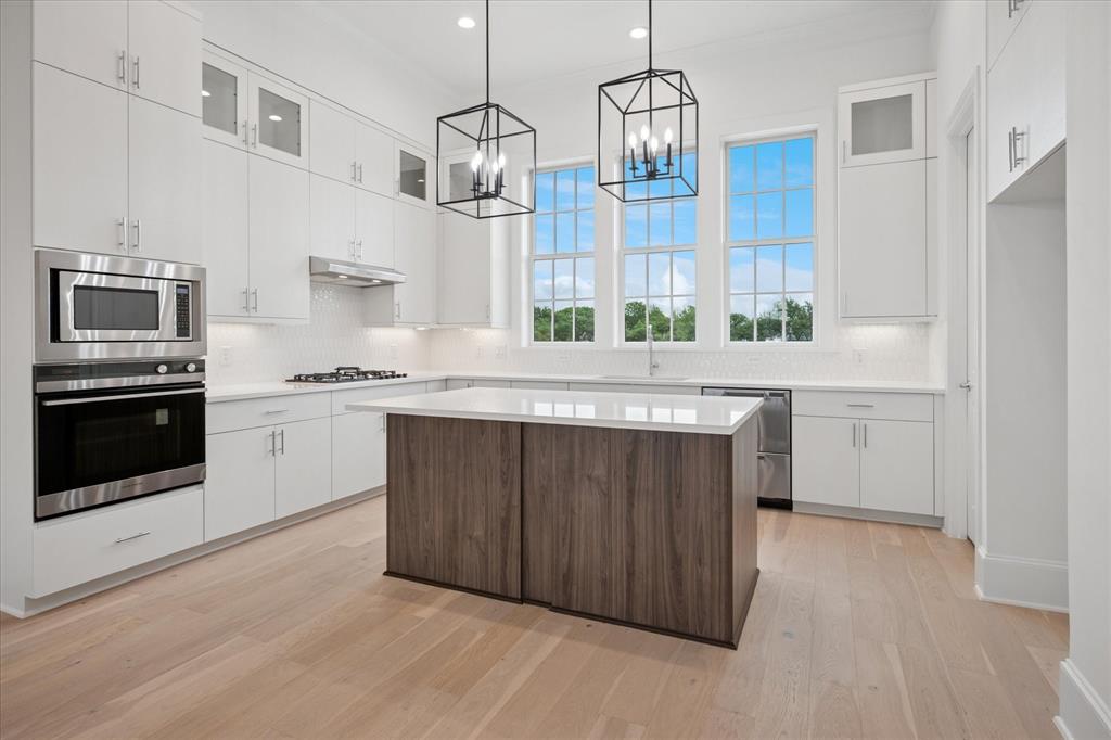Kitchen featuring glass insert cabinets, white cabinetry, stainless steel appliances, a center island, and backsplash