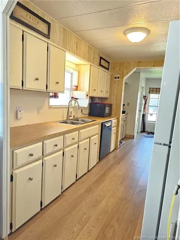a kitchen with a sink dishwasher stove and white cabinets with wooden floor