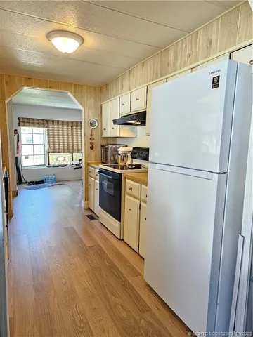 a kitchen with a refrigerator a stove top oven a sink dishwasher and wooden floor