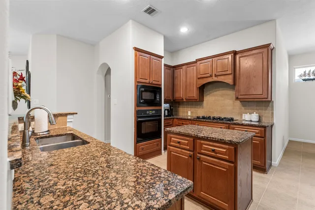 a kitchen with stainless steel appliances granite countertop a stove a sink and a refrigerator