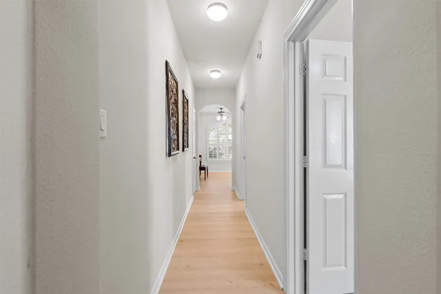 a view of a hallway with wooden floor and a bathroom