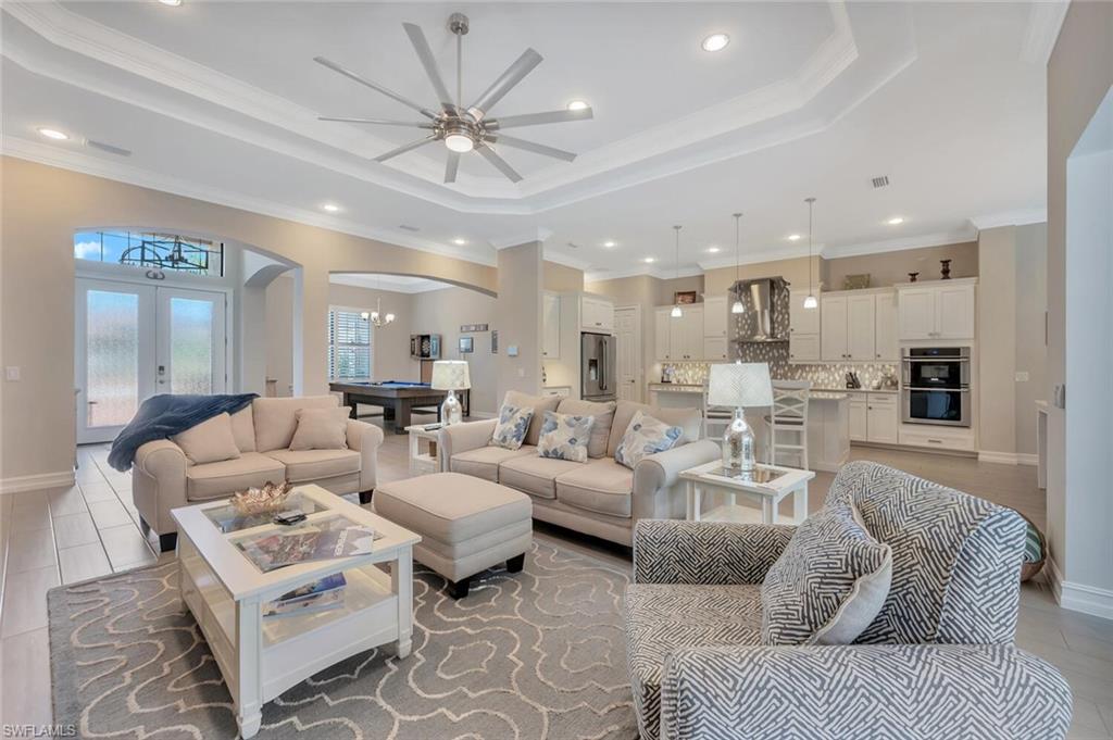 a living room with furniture kitchen view and a chandelier