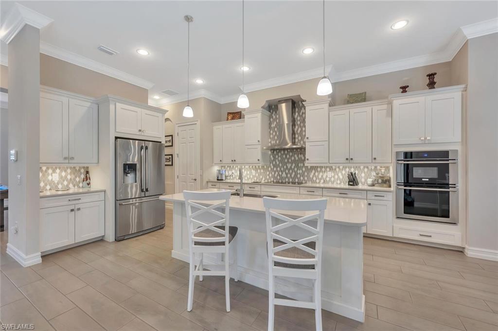 1451 Mockingbird Drive Naples, FL 34120 - Photo 13 of 42 a large kitchen with kitchen island white cabinets and stainless steel appliances