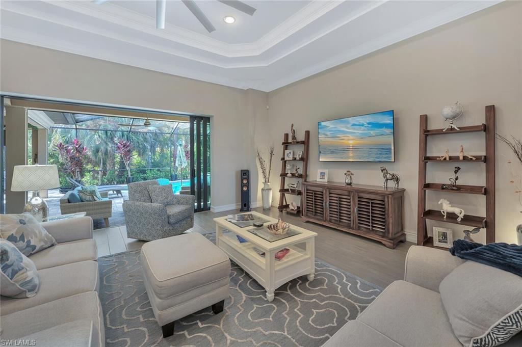 1451 Mockingbird Drive Naples, FL 34120 - Photo 7 of 42 a living room with furniture a flat screen tv and a floor to ceiling window