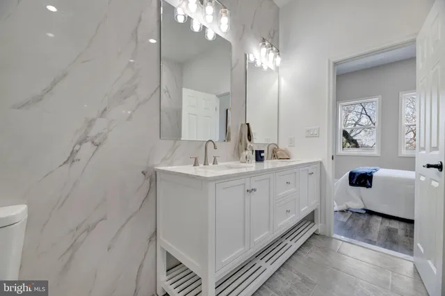 a spacious bathroom with a double vanity sink a toilet a mirror and shower