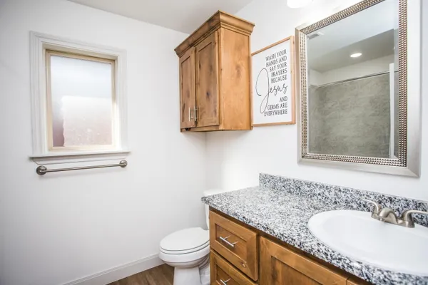 a bathroom with a granite countertop sink a toilet and a mirror