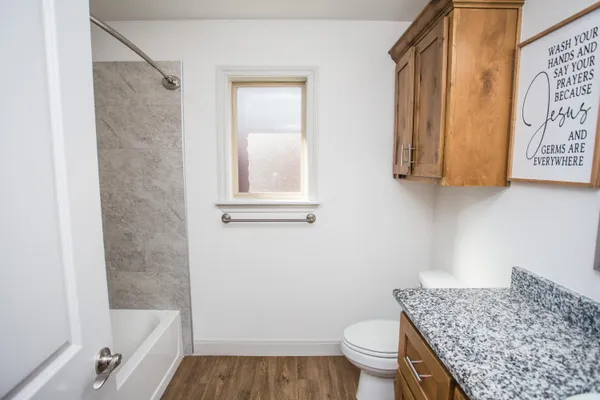 a bathroom with a granite countertop bathtub shower sink and toilet