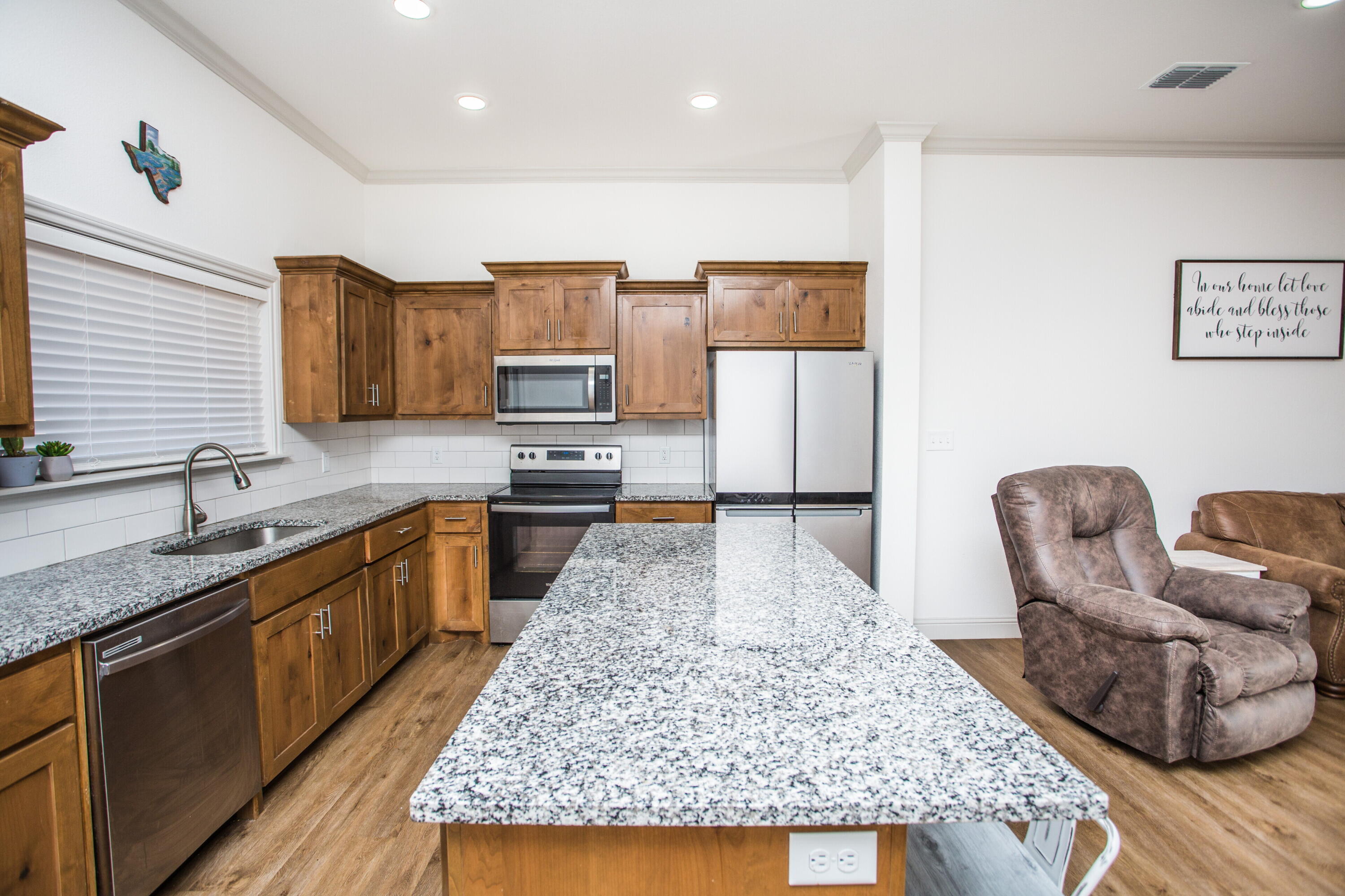 816 North 4th Street Wolfforth, TX 79382 - Photo 10 of 25 a large kitchen with kitchen island granite countertop wooden cabinets a granite counter tops and a view of living room