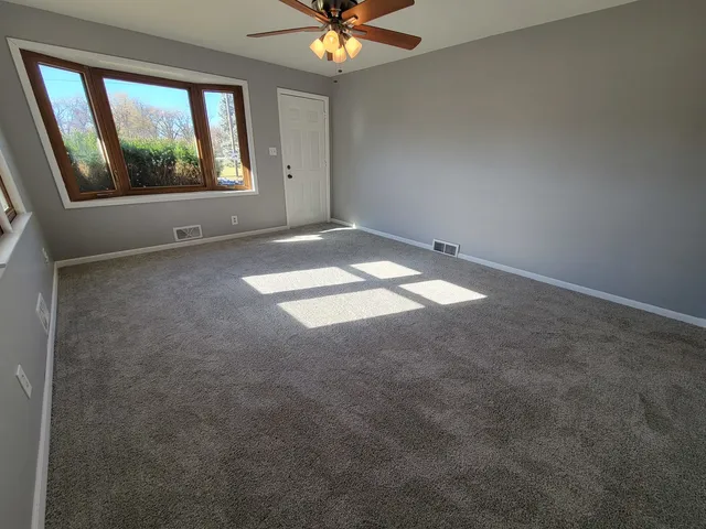 an empty room with windows and fan