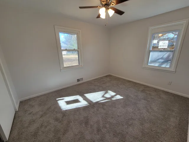 an empty room with windows and fan