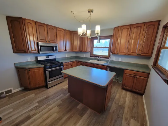 a kitchen with wooden floors a sink cabinets and microwave