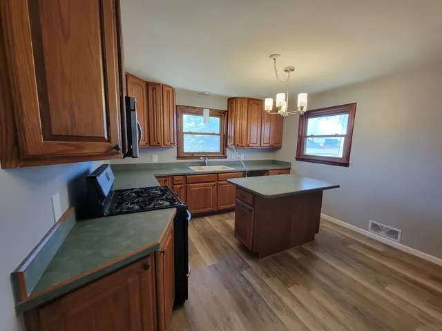 a kitchen with granite countertop a stove a sink dishwasher and a microwave oven with cabinets