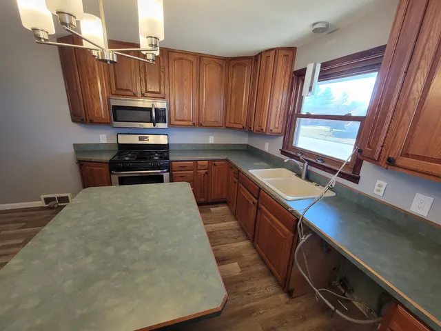 a kitchen with stainless steel appliances a sink a stove a microwave a sink and cabinets