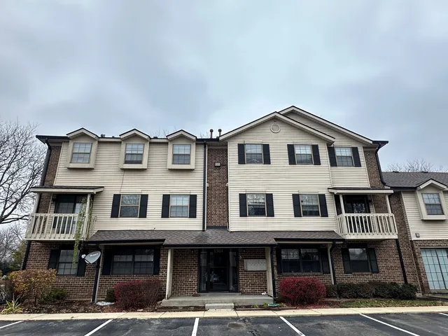 a front view of a residential apartment building with a yard and a garage