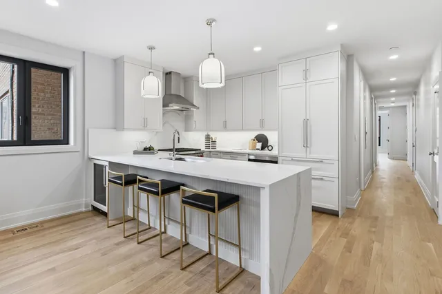 a kitchen with kitchen island stainless steel appliances a dining table chairs sink and wooden floor