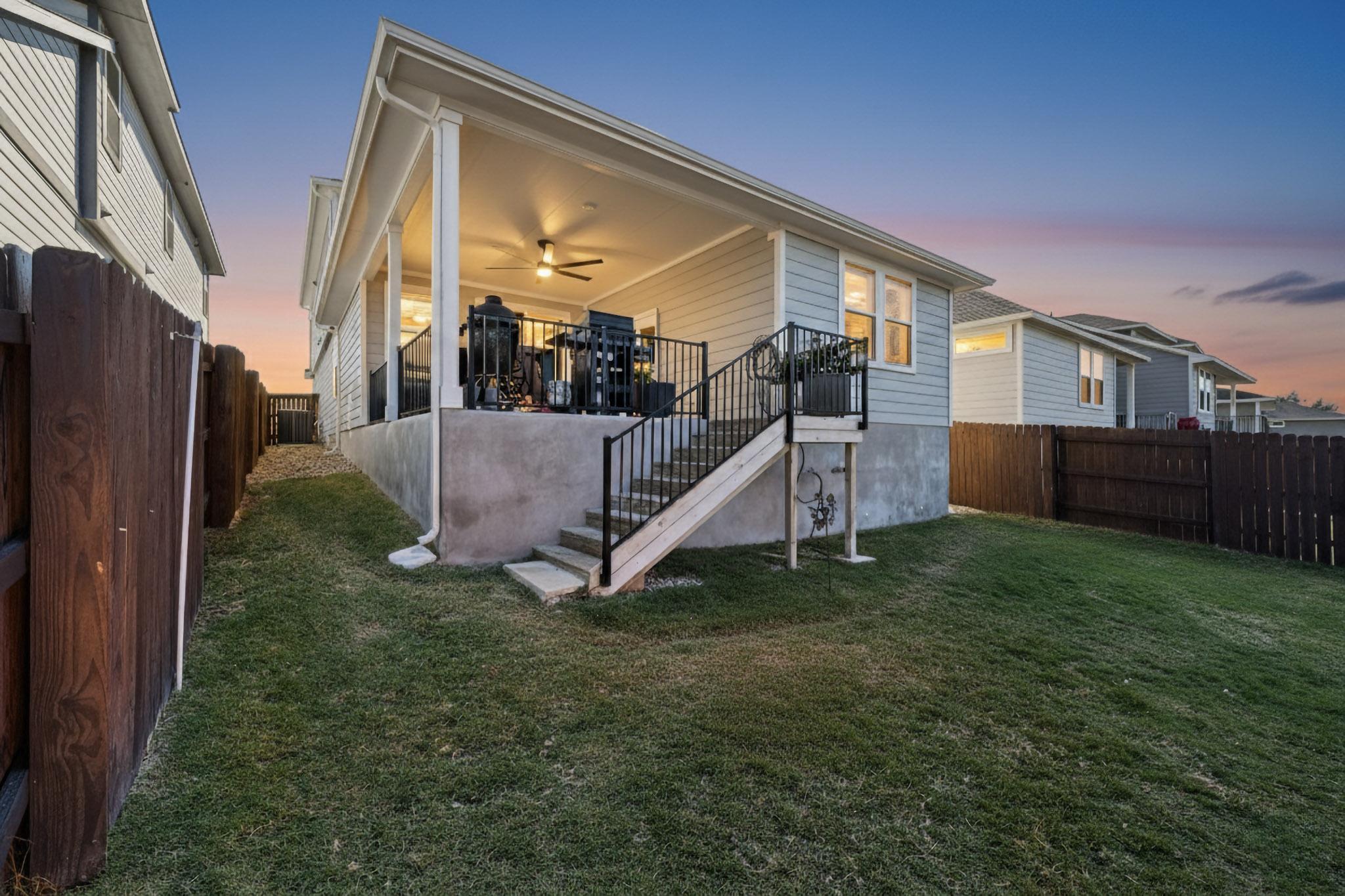 473 Bauer Loop Liberty Hill, TX 78642 - Photo 35 of 38 Back of property at dusk with ceiling fan, stairway, a fenced backyard, and a patio
