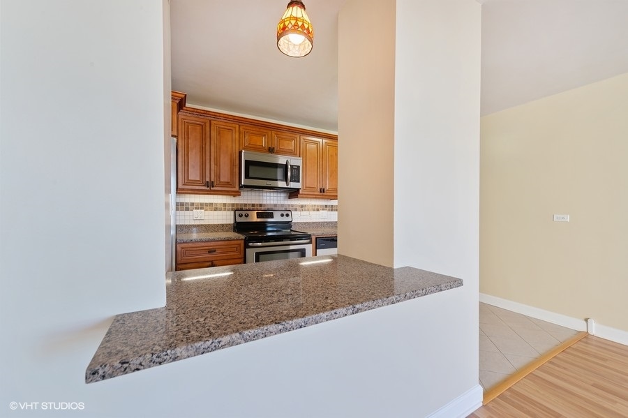 5701 North Sheridan Road, Unit 21H Chicago, IL 60660 - Photo 7 of 14 a kitchen with granite countertop a stove and a microwave