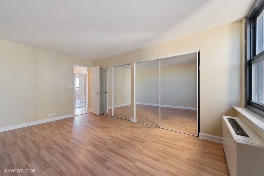 5701 North Sheridan Road, Unit 21H Chicago, IL 60660 - Photo 8 of 14 a view of an empty room with wooden floor and a window