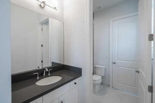 a bathroom with a granite countertop sink toilet a mirror and shower