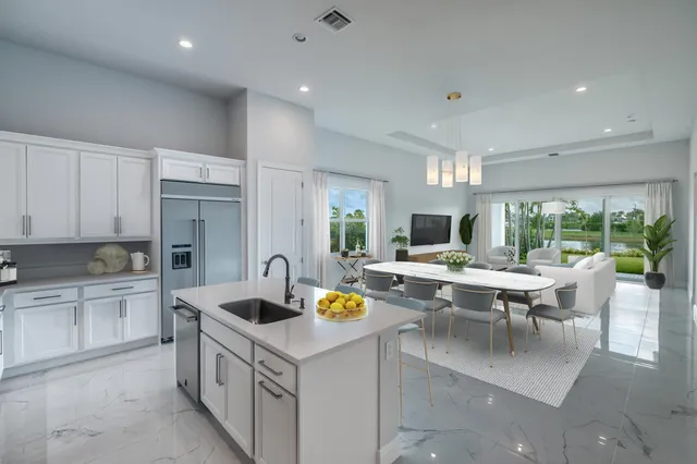 a living room with stainless steel appliances granite countertop a white cabinets and couches chair