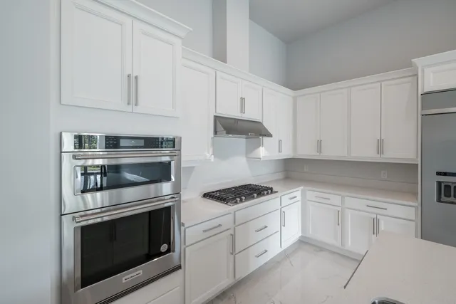 a kitchen with white cabinets and stainless steel appliances