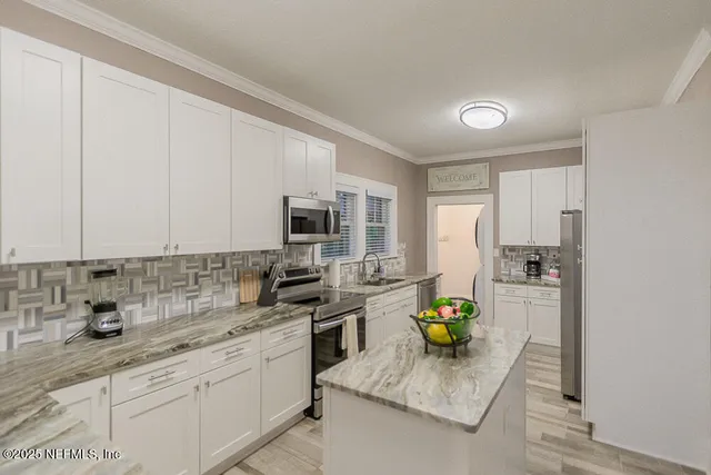 a kitchen with a sink white cabinets and appliances