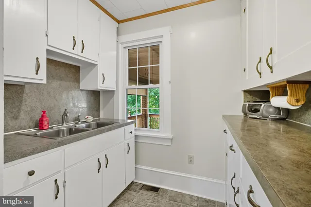 a kitchen with white cabinets and window