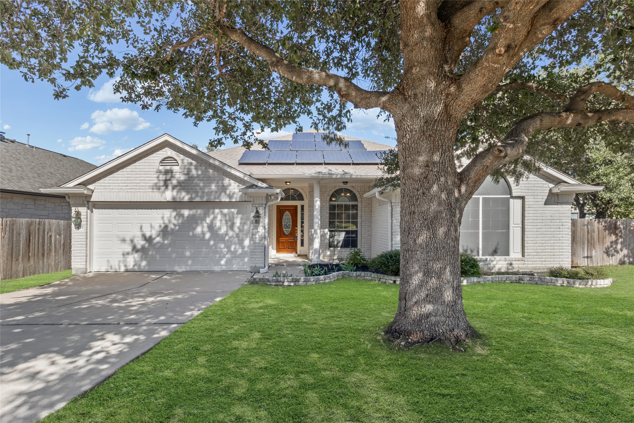 14901 Staked Plains Loop Austin, TX 78717 - Photo 1 of 30 View of front facade featuring driveway, an attached garage, brick siding, covered porch, and solar panels