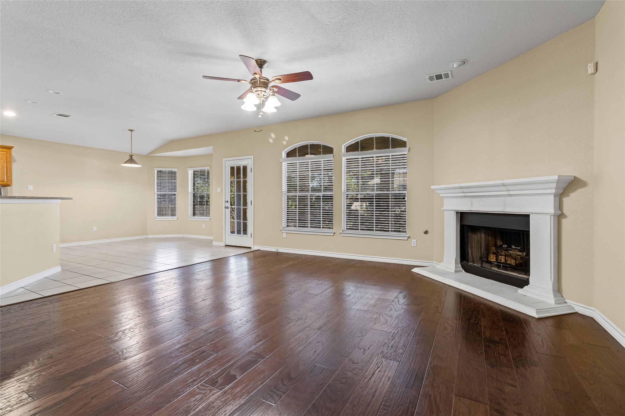 14901 Staked Plains Loop Austin, TX 78717 - Photo 8 of 30 Living room featuring a fireplace with raised hearth, plenty of natural light, light wood-style floors, ceiling fan, and a textured ceiling