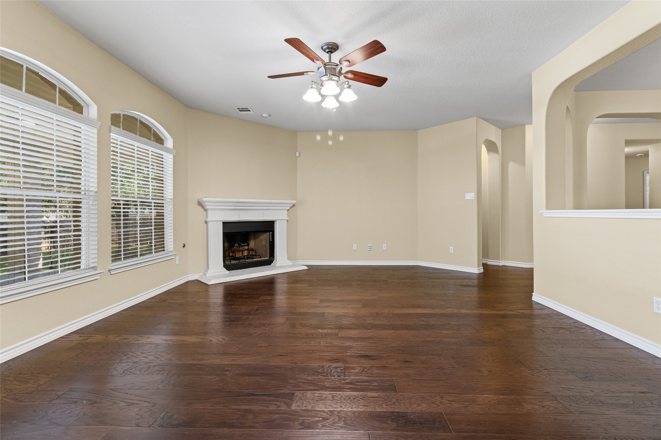 14901 Staked Plains Loop Austin, TX 78717 - Photo 9 of 30 Living room with wood flooring, a fireplace with raised hearth, ceiling fan, and arched walkways
